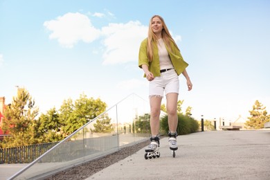 Photo of Happy woman roller skating on city street. Space for text