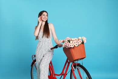 Photo of Smiling woman and bicycle with basket of flowers against light blue background