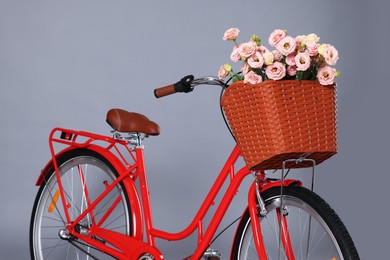 Photo of Bicycle with basket of beautiful flowers on grey background