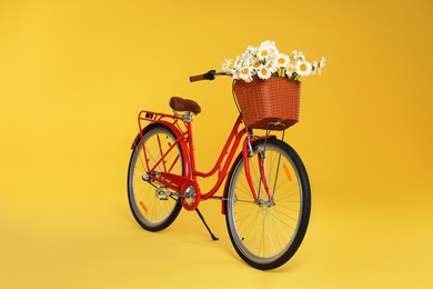 Photo of Bicycle with basket of beautiful flowers on yellow background