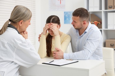 Photo of In vitro fertilization (IVF). Upset couple having consultation with doctor in reproductive clinic