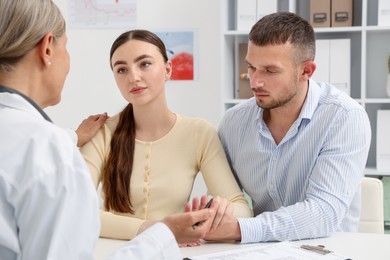 Photo of In vitro fertilization (IVF). Upset couple having consultation with doctor in reproductive clinic