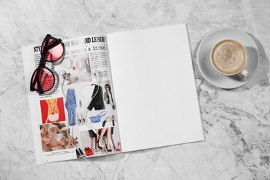 Photo of Open magazine, sunglasses and coffee on white marble background, flat lay. Mockup for design
