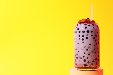 Photo of Tasty milk bubble tea in glass on yellow background, space for text