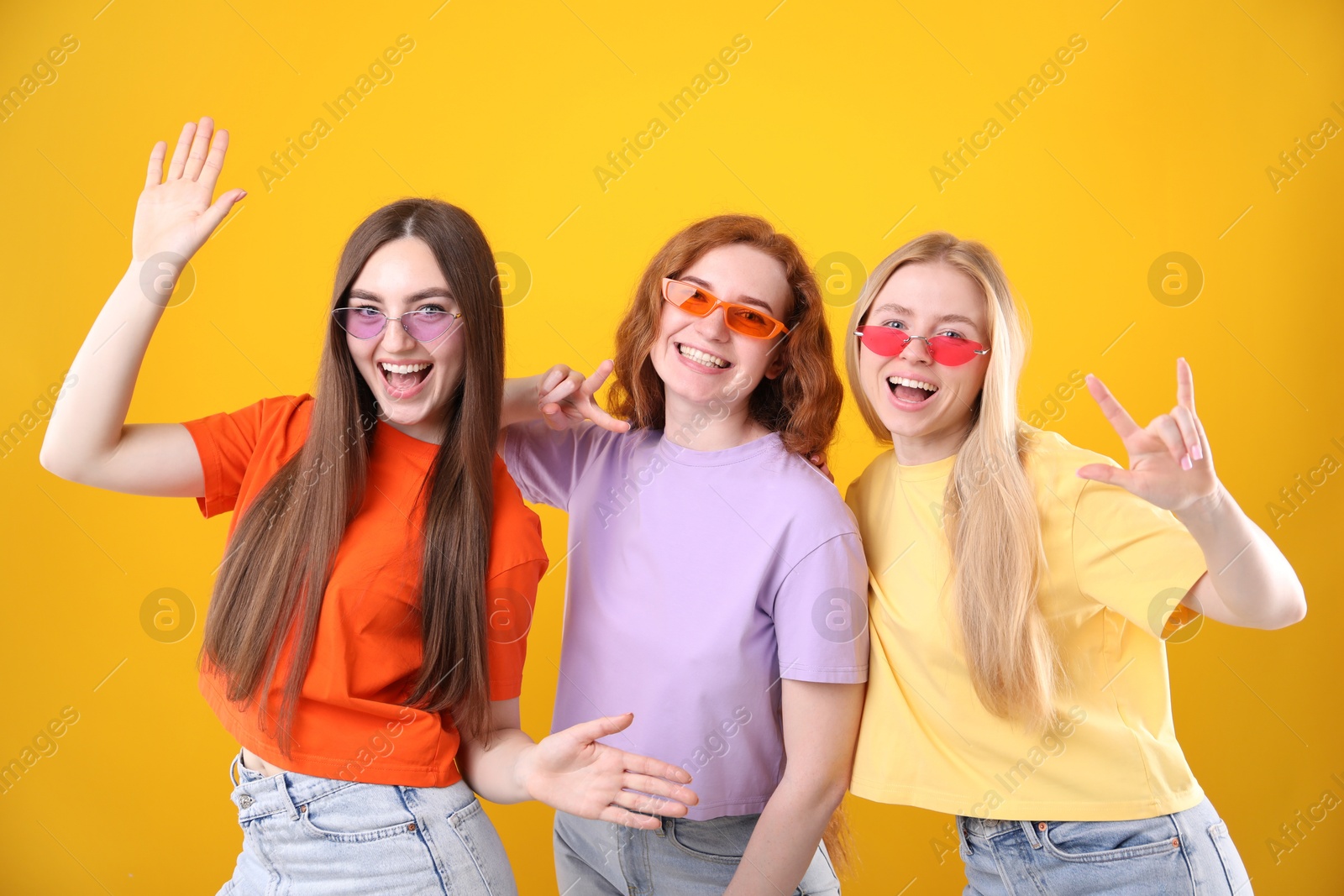Photo of Beautiful women with different hair colors wearing stylish sunglasses on orange background
