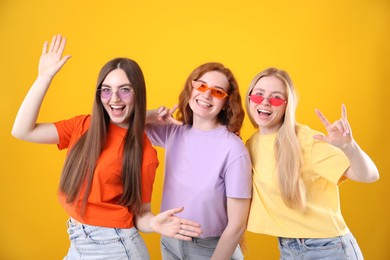 Photo of Beautiful women with different hair colors wearing stylish sunglasses on orange background