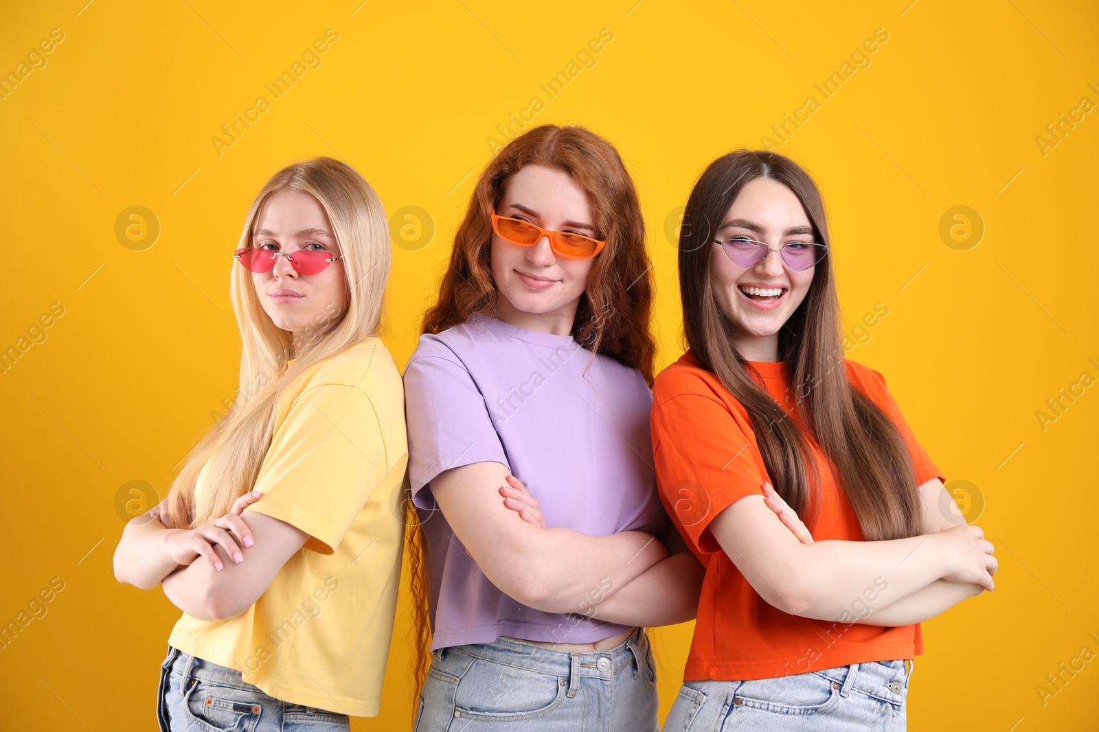 Beautiful women with different hair colors wearing stylish sunglasses on orange background Photo of Beautiful women with different hair colors wearing stylish sunglasses on orange background