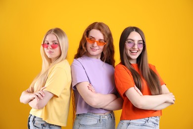 Photo of Beautiful women with different hair colors wearing stylish sunglasses on orange background