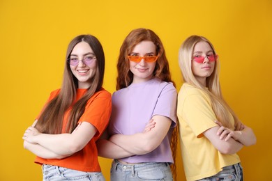 Photo of Beautiful women with different hair colors wearing stylish sunglasses on orange background