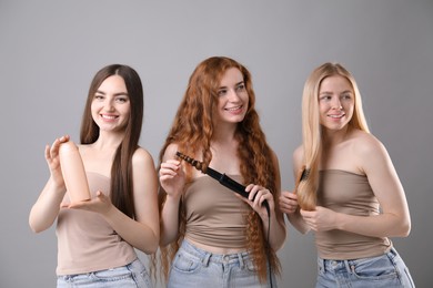 Photo of Beautiful women with different hair colors holding curling iron, shampoo and brush on grey background