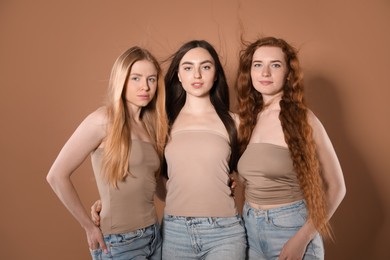 Photo of Beautiful women with different hair colors on dark beige background