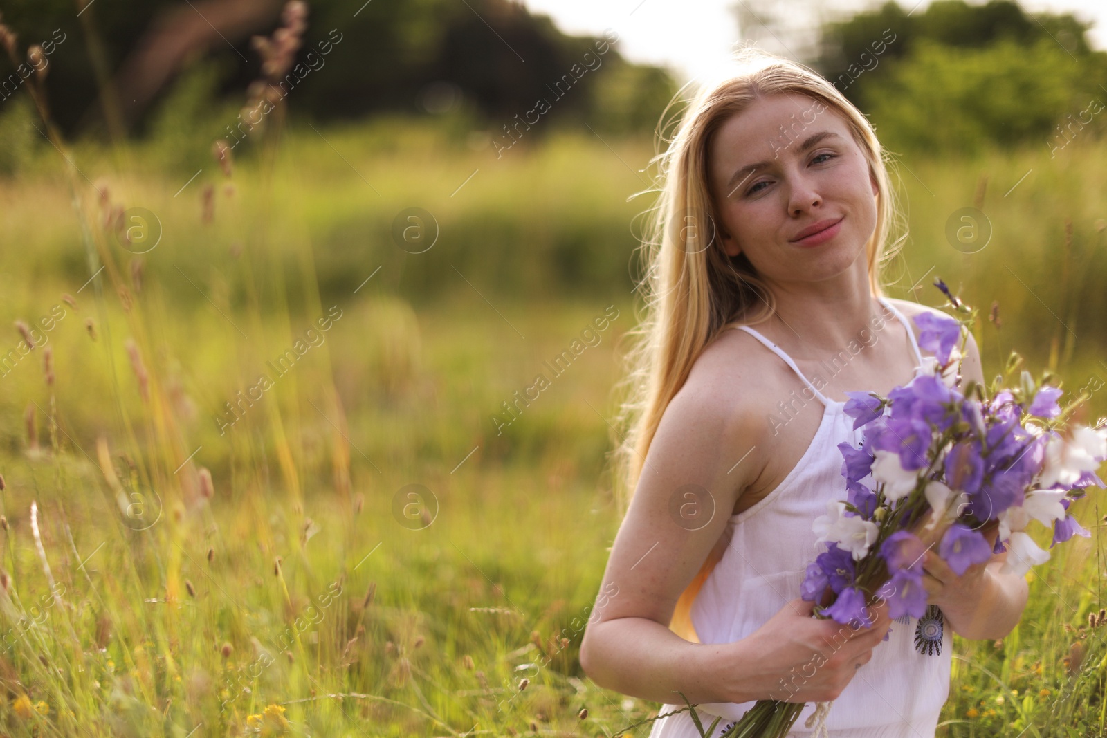 Beautiful woman with bouquet of wildflowers enjoying sunny day in meadow. Space for text Photo of Beautiful woman with bouquet of wildflowers enjoying sunny day in meadow. Space for text