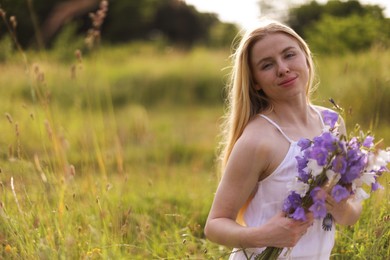 Photo of Beautiful woman with bouquet of wildflowers enjoying sunny day in meadow. Space for text
