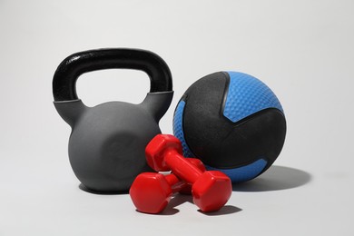 Photo of Medicine balls, kettlebell and dumbbells on light grey background