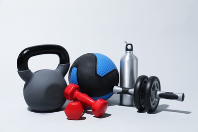 Photo of Medicine ball, kettlebell, water bottle, ab wheel and dumbbells on light grey background