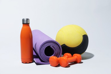Photo of Medicine ball, dumbbells, water bottle and fitness mat on light grey background