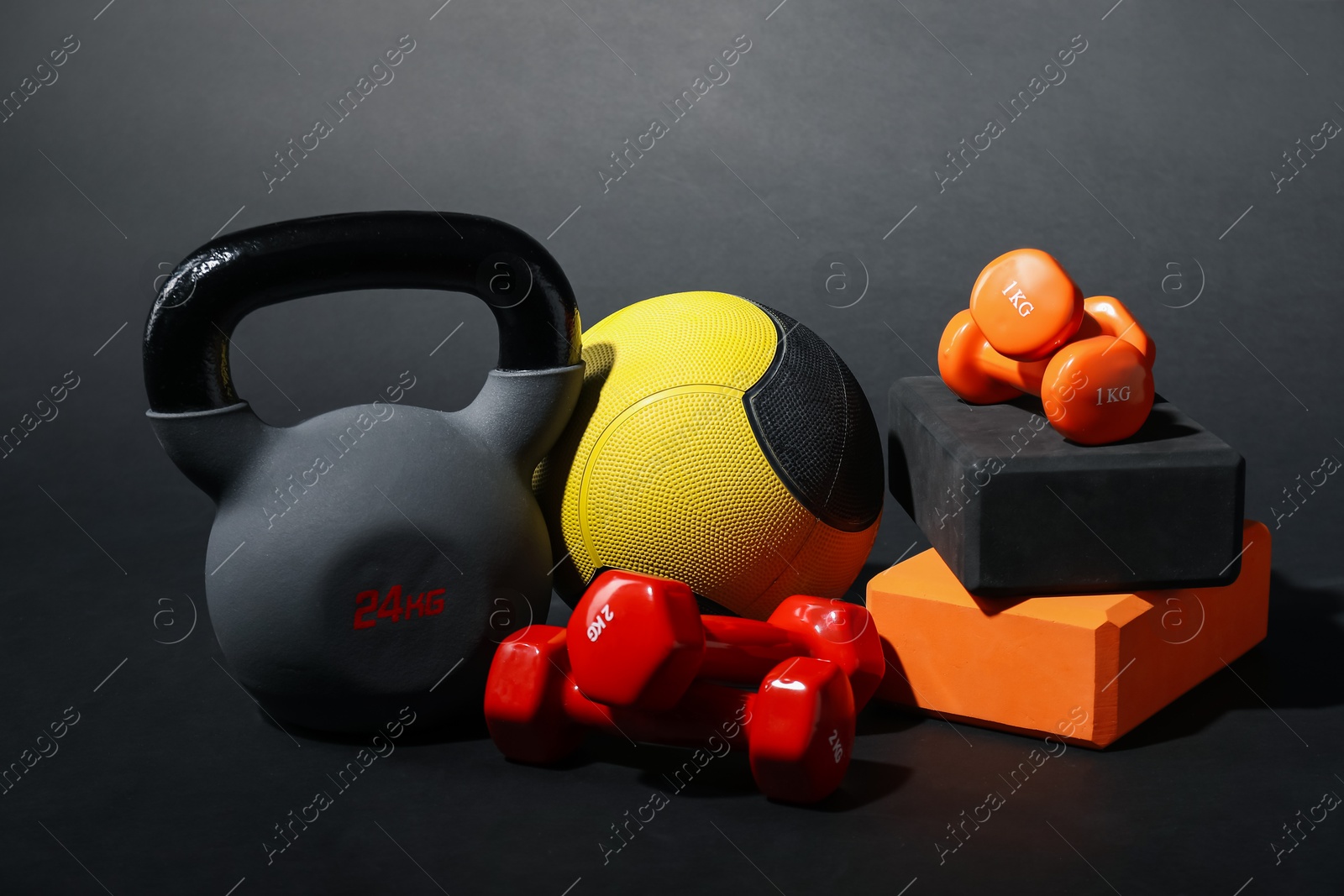 Medicine ball, dumbbells, foam blocks and kettlebell on black background Photo of Medicine ball, dumbbells, foam blocks and kettlebell on black background