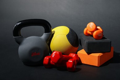 Photo of Medicine ball, dumbbells, foam blocks and kettlebell on black background