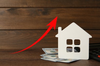 Image of Increase in real estate value. House model and money on table. Growing price represented by arrow