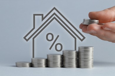 Image of Increase in real estate value. Woman stacking coins against grey background, closeup. House illustration with percent sign