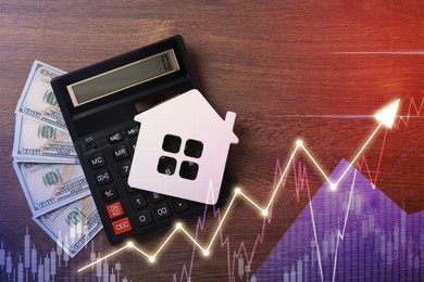 Image of Increase in real estate value. House model, money and calculator on table, top view. Growing price represented by graph and arrow