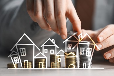 Image of Increase in real estate value. Man stacking coins at table, closeup. Illustration of houses