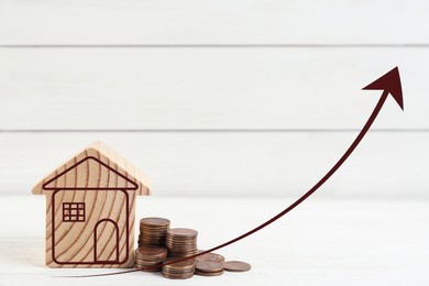Image of Increase in real estate value. House model and coins on table. Growing price represented by arrow