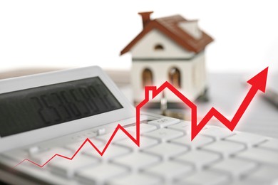 Image of Increase in real estate value. House model and calculator on table. Growing price represented by arrow