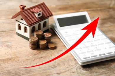 Image of Increase in real estate value. House model, coins and calculator on table. Growing price represented by arrow