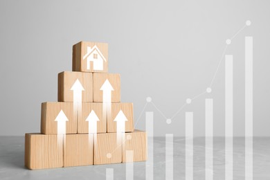 Image of Increase in real estate value. Wooden cubes with arrows and house icon on table. Growing price represented by graph