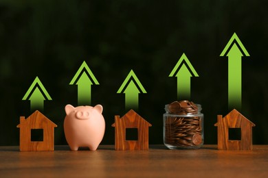 Image of Increase in real estate value. House models, jar of coins and piggy bank on table. Growing price represented by arrows