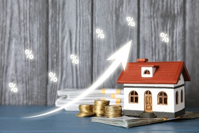 Image of Increase in real estate value. House model and money on table. Growing price represented by arrow and percent signs