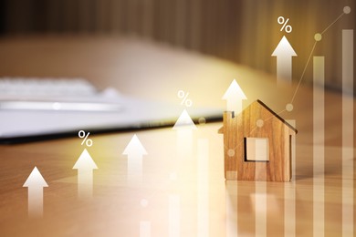 Image of Increase in real estate value. House model and documents on table. Growing price represented by graph, percent signs and arrows