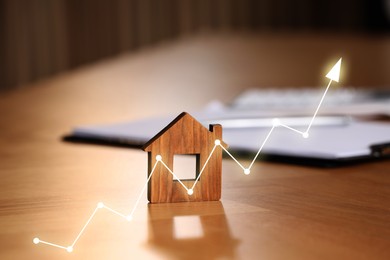 Image of Increase in real estate value. House model and documents on table. Growing price represented by arrow