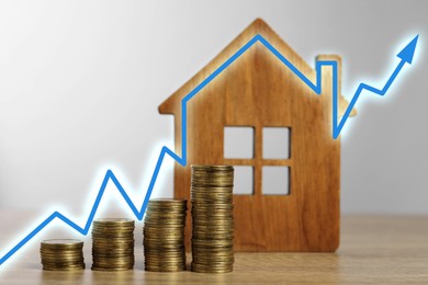 Image of Increase in real estate value. House model and coins on table. Growing price represented by arrow