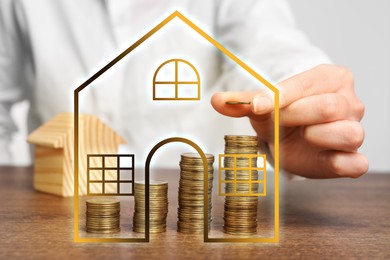 Image of Increase in real estate value. Woman stacking coins at table, closeup. Illustration of house