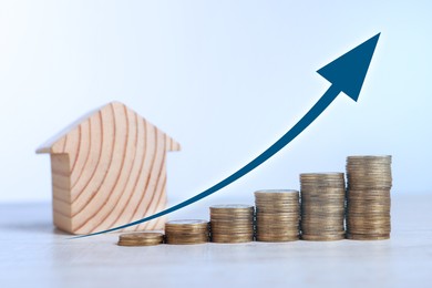 Image of Increase in real estate value. House model and coins on table. Growing price represented by arrow