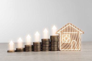 Image of Increase in real estate value. House model and coins on table. Growing price represented by arrows