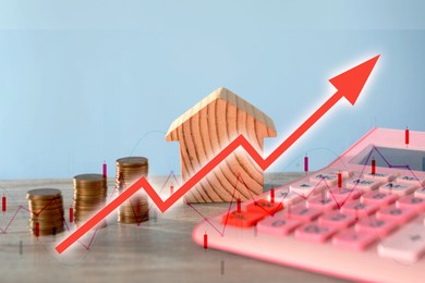 Image of Increase in real estate value. House model, coins and calculator on table. Growing price represented by graph and arrow