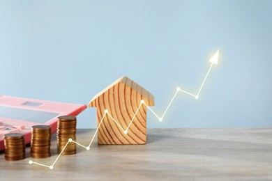 Image of Increase in real estate value. House model, coins and calculator on table. Growing price represented by arrow