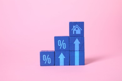Image of Increase in real estate value. Blue cubes with house icon, arrows and percent signs on pink background