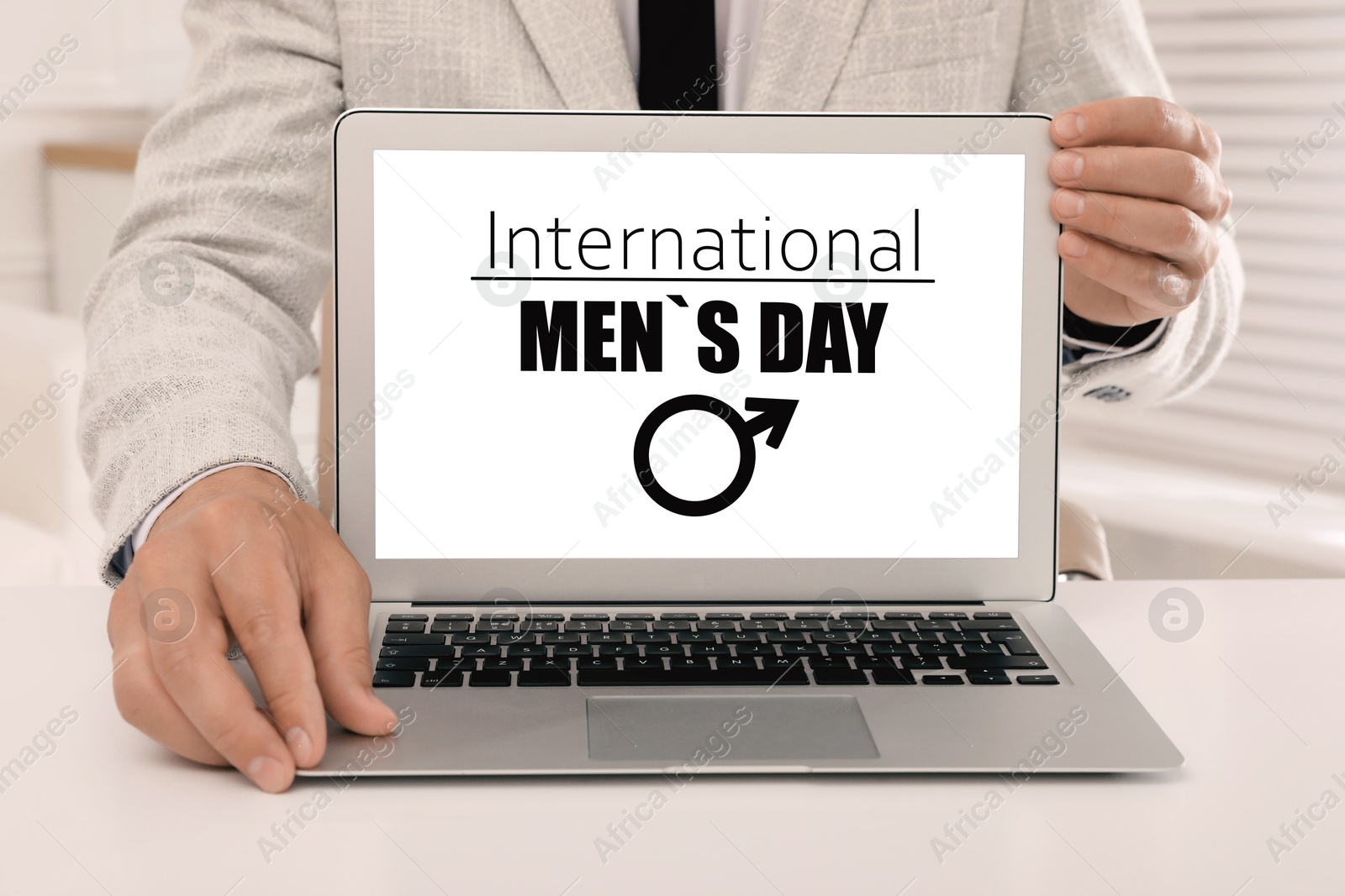 International Men's Day. Man showing laptop with text and male sign on screen Image of International Men's Day. Man showing laptop with text and male sign on screen