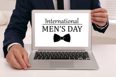 Image of International Men's Day. Man showing laptop with text and bowtie on screen