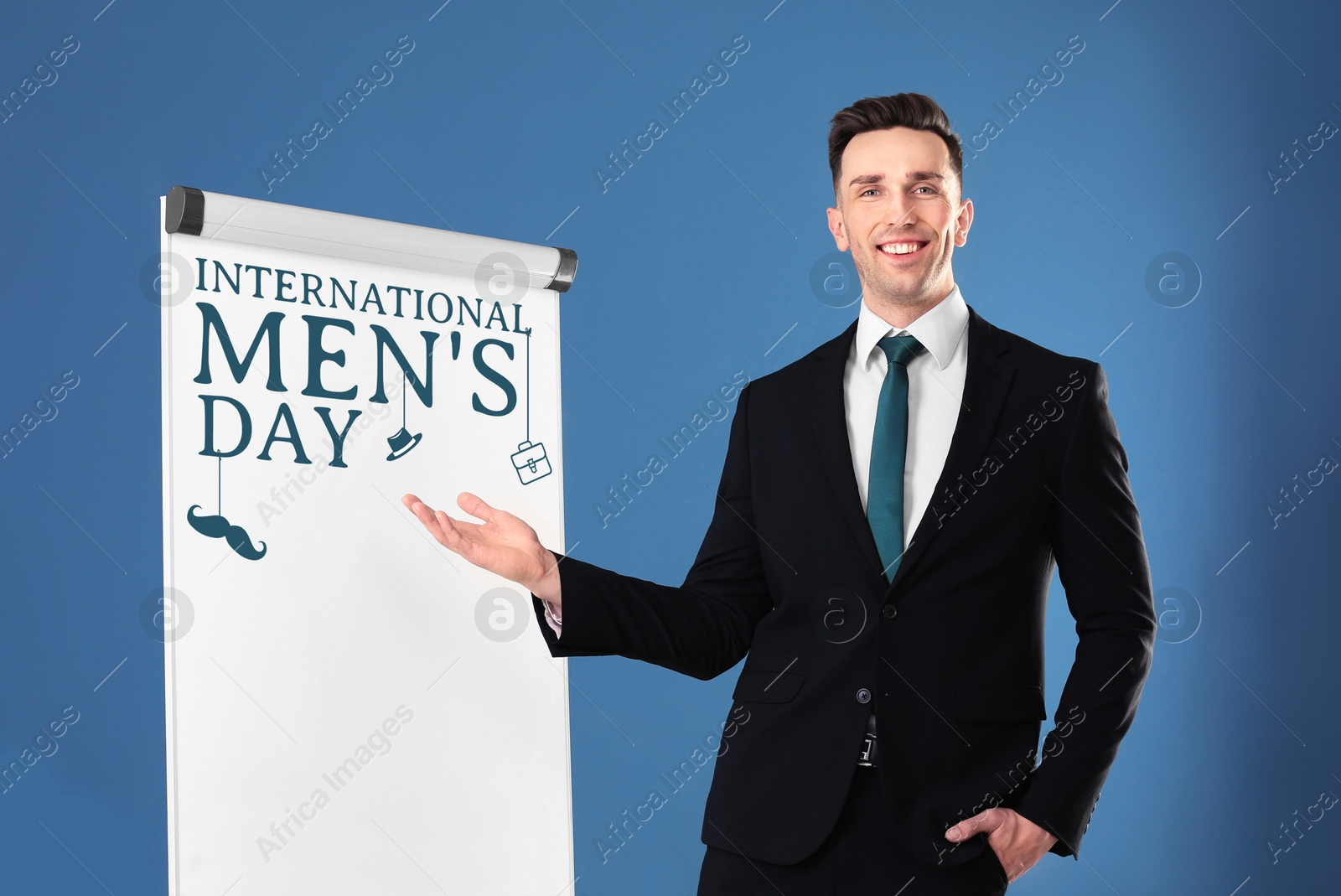 International Men's Day card. Happy man pointing at board against blue background Image of International Men's Day card. Happy man pointing at board against blue background