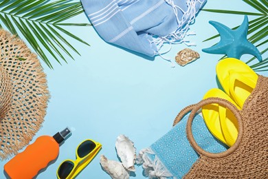 Photo of Flat lay composition with different beach accessories and palm leaf on light blue background, space for text