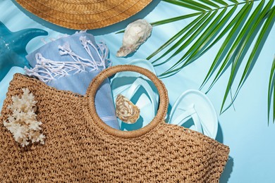Photo of Flat lay composition with different beach accessories and palm leaf on light blue background
