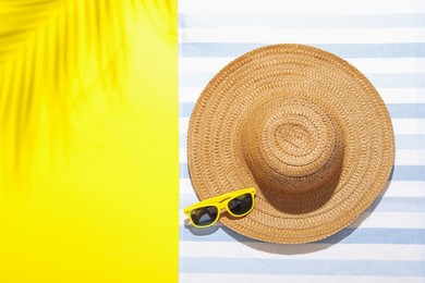 Photo of Beach towel, straw hat and sunglasses on yellow background, top view. Space for text