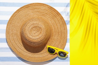 Photo of Beach towel, straw hat and sunglasses on yellow background, top view. Space for text