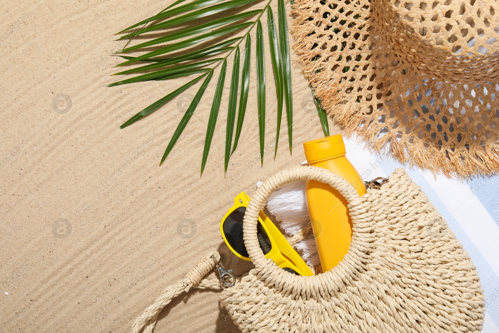Different beach accessories and palm leaf on sand outdoors, flat lay. Space for text Photo of Different beach accessories and palm leaf on sand outdoors, flat lay. Space for text