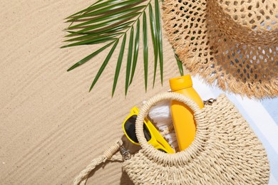 Photo of Different beach accessories and palm leaf on sand outdoors, flat lay. Space for text